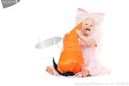 Image of Happy baby girl plays with a carrot