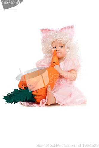 Image of Baby girl plays with a carrot. Isolated