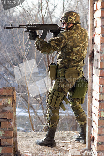 Image of Soldier standing near wall with a gun