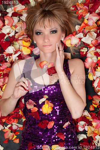 Image of young blonde lying in rose petals
