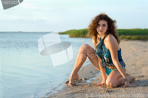 Image of Beautiful young woman sitting on the bay