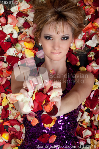 Image of charming young blonde lying in rose petals