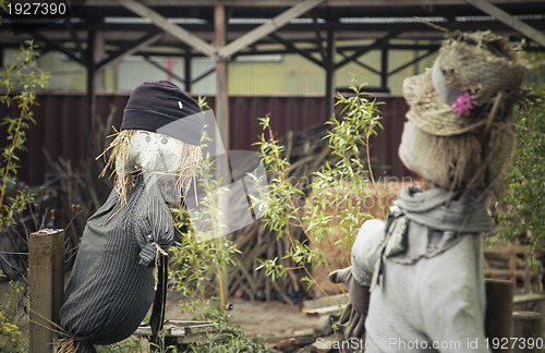 Image of Two scarecrows outside a barn