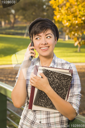 Image of Mixed Race Female Student Holding Books and Talking on Phone