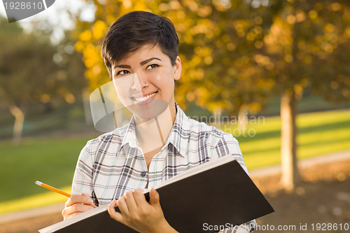 Image of Mixed Race Young Female Holding Sketch Book and Pencil Outdoors