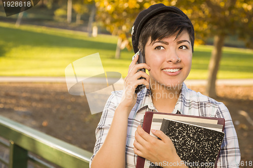 Image of Mixed Race Female Student Holding Books and Talking on Phone