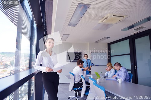 Image of business woman with her staff in background at office