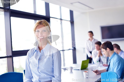 Image of business woman with her staff in background at office