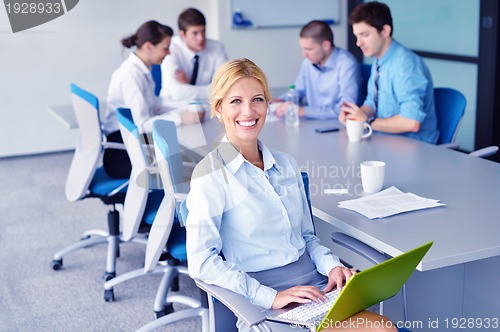 Image of business woman with her staff in background at office