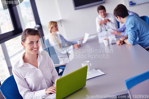 Image of business woman with her staff in background at office