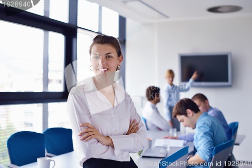 Image of business woman with her staff in background at office