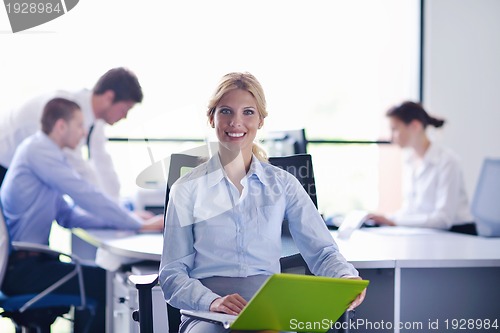 Image of business woman with her staff in background at office