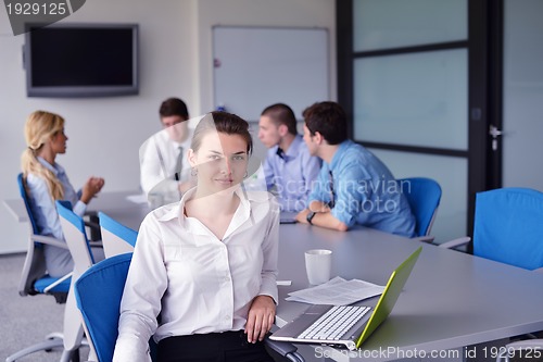 Image of business woman with her staff in background at office