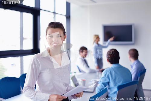 Image of business woman with her staff in background at office