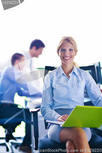 Image of business woman with her staff in background at office