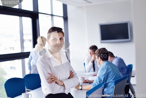 Image of business woman with her staff in background at office