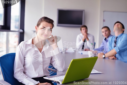 Image of business woman with her staff in background at office