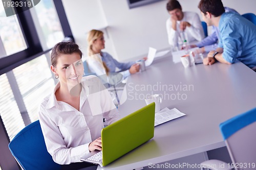 Image of business woman with her staff in background at office