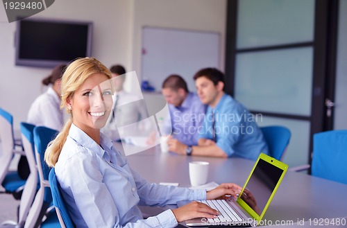 Image of business woman with her staff in background at office
