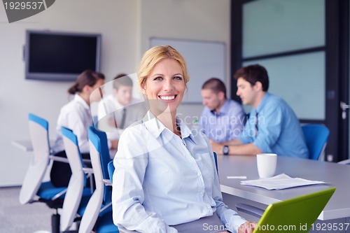 Image of business woman with her staff in background at office