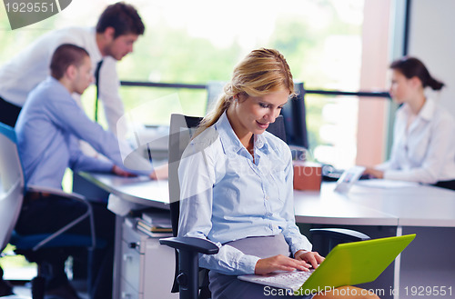Image of business woman with her staff in background at office