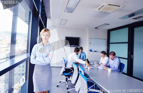 Image of business woman with her staff in background at office