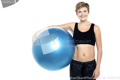 Image of An attractive fit lady holding blue pilates ball