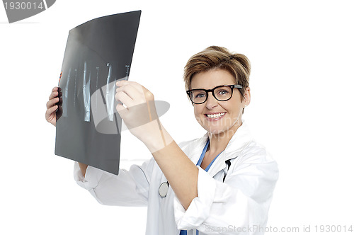 Image of Experienced female doctor examining x-ray report