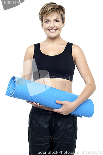 Image of Health conscious woman holding blue exercise mat