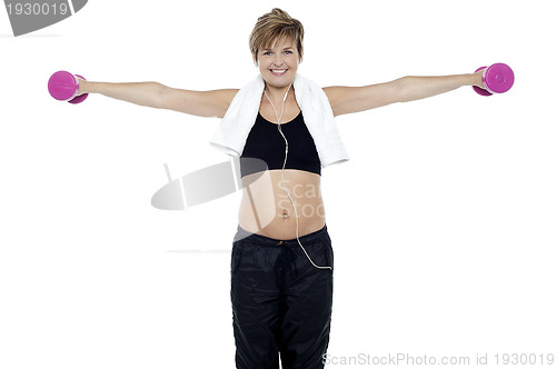Image of Lady enjoying music and exercising with dumbbells