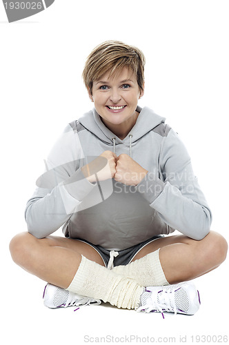 Image of Adorable woman in sports wear sitting on the floor