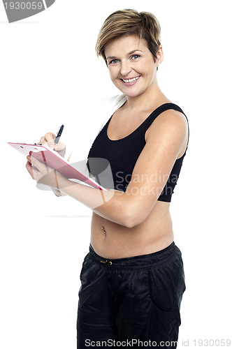 Image of Female gym instructor writing diet chart