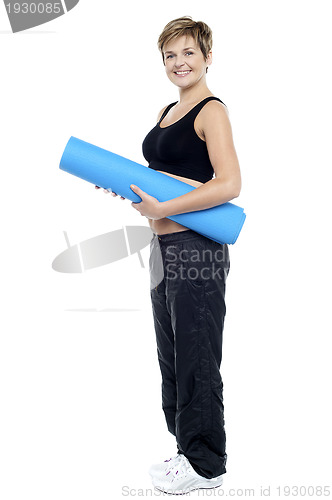 Image of Smiling female instructor carrying a blue yoga mat