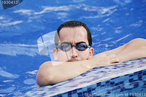 Image of Male Swimmer resting after several laps in the indoor swimming p