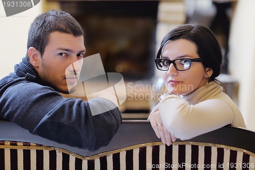 Image of Young romantic couple sitting and relaxing in front of fireplace