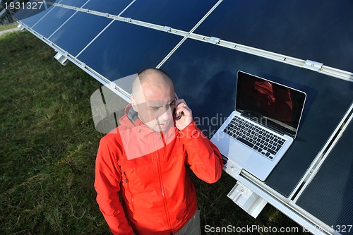 Image of engineer using laptop at solar panels plant field