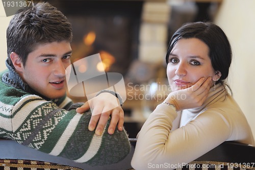 Image of Young romantic couple sitting and relaxing in front of fireplace