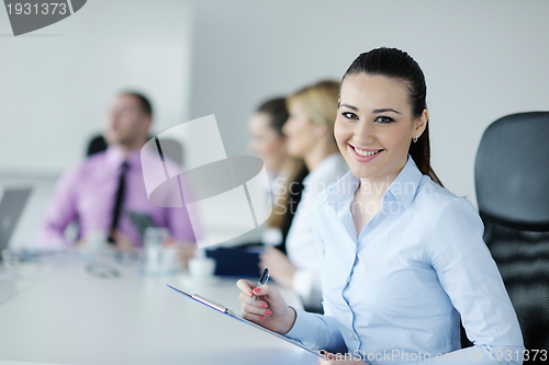 Image of business woman standing with her staff in background