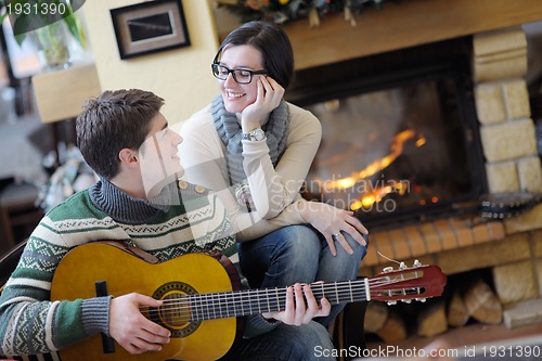 Image of Young romantic couple sitting and relaxing in front of fireplace