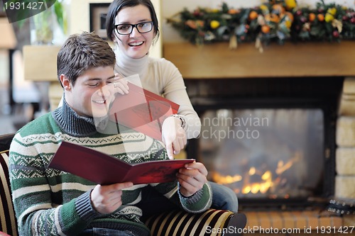 Image of Young romantic couple sitting and relaxing in front of fireplace