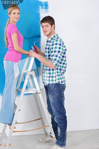 Image of happy couple paint wall at new home