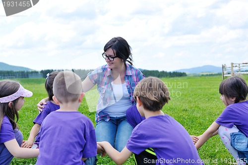 Image of happy kids group with teacher in nature