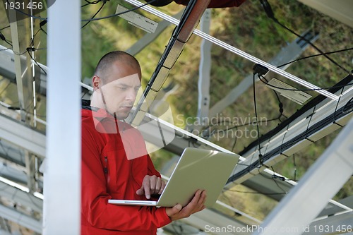 Image of engineer using laptop at solar panels plant field