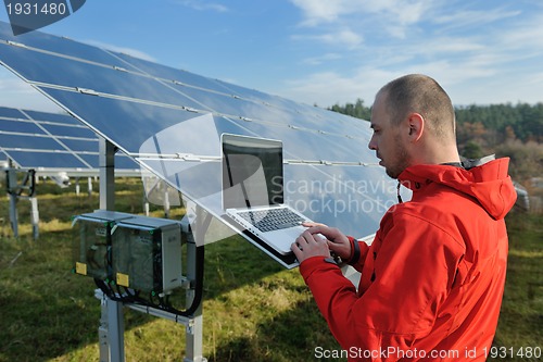 Image of engineer using laptop at solar panels plant field