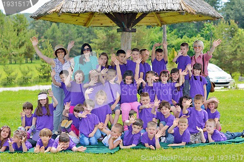 Image of happy kids group with teacher in nature