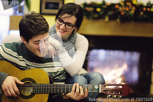 Image of Young romantic couple sitting on sofa in front of fireplace at h