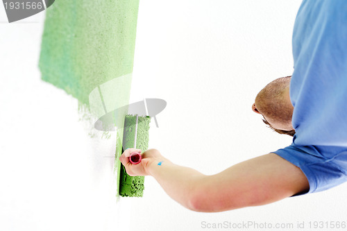 Image of handsome young man paint white wall in color