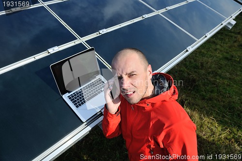 Image of engineer using laptop at solar panels plant field