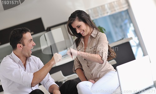 Image of joyful couple relax and work on laptop computer at modern home