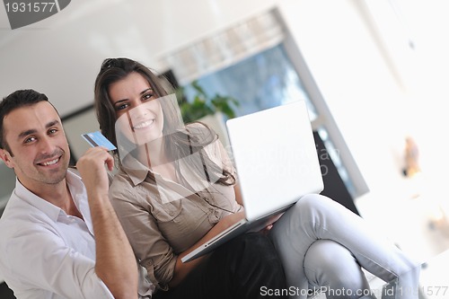 Image of joyful couple relax and work on laptop computer at modern home